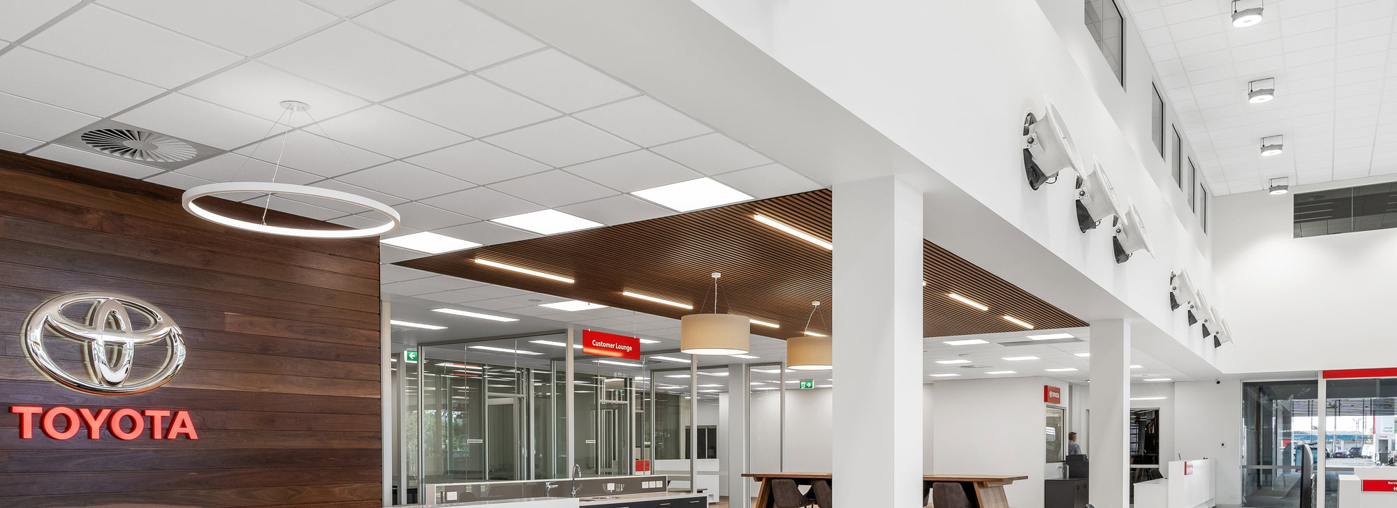 Toyota dealership interior featuring Armstrong Ceiling tiles with reception desk and showroom in the background